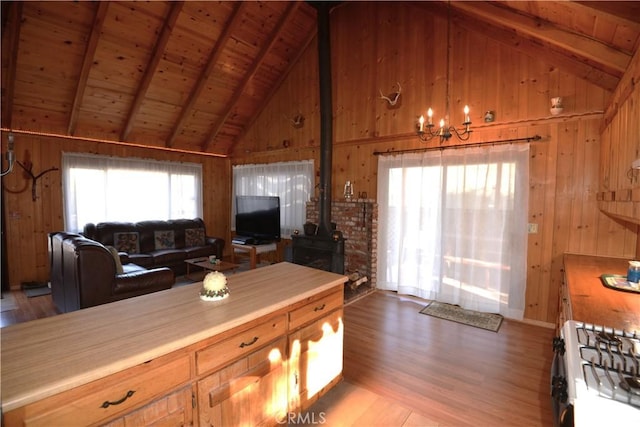 kitchen featuring a wood stove, wooden ceiling, wooden walls, light hardwood / wood-style floors, and white range with gas cooktop