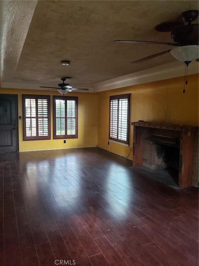 unfurnished living room featuring a raised ceiling, a healthy amount of sunlight, and hardwood / wood-style flooring