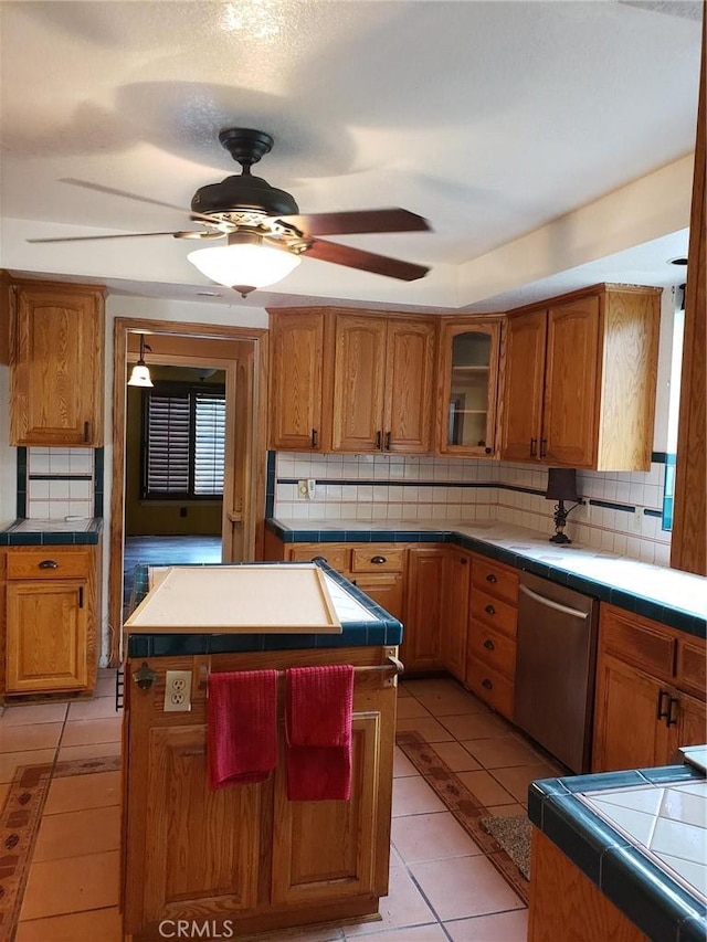 kitchen with light tile patterned flooring, tile countertops, dishwasher, and a center island