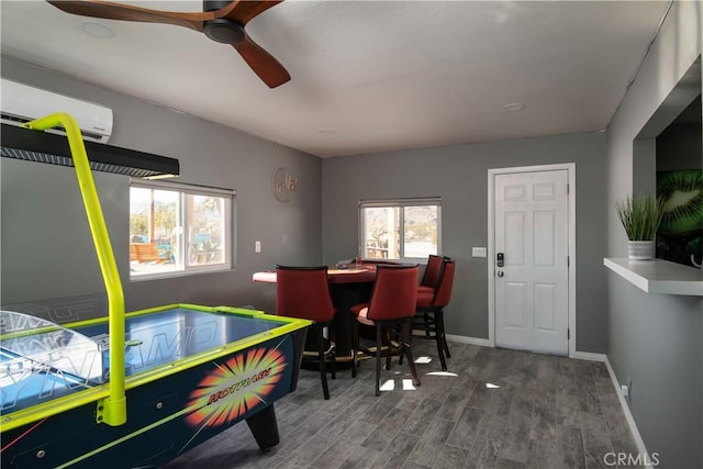 game room with ceiling fan, a wall mounted AC, and hardwood / wood-style flooring