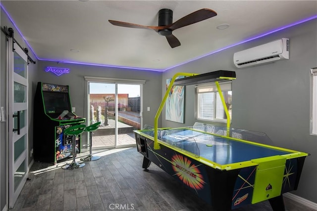 playroom with ceiling fan, a barn door, dark hardwood / wood-style floors, and a wall mounted air conditioner