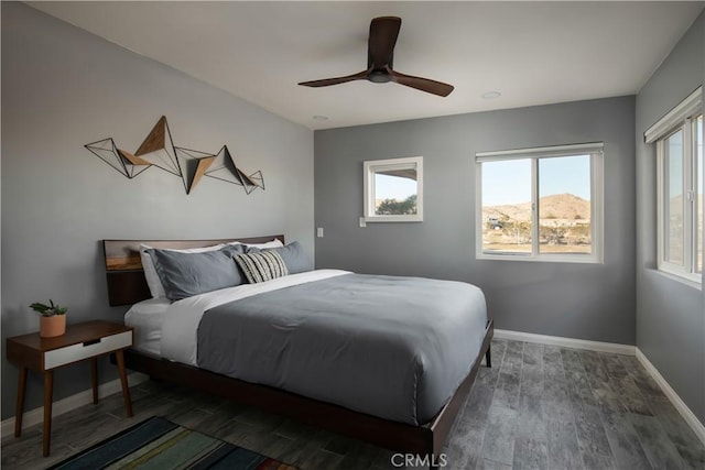 bedroom with ceiling fan, dark wood-type flooring, and a mountain view