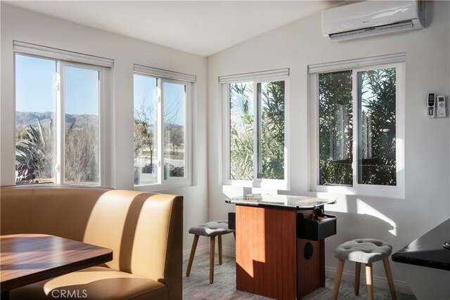 sunroom / solarium with vaulted ceiling, a mountain view, and an AC wall unit