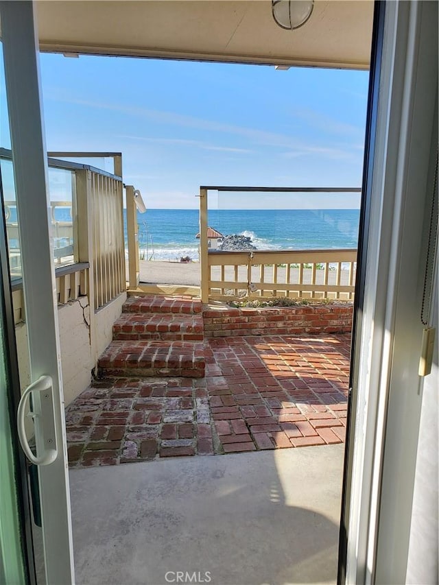 balcony with a water view and a view of the beach