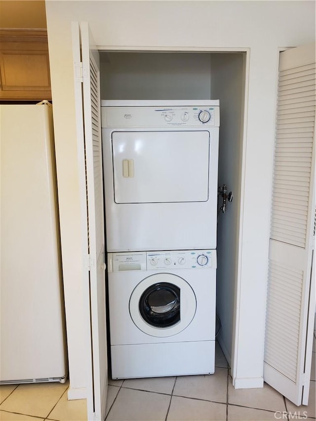 washroom featuring stacked washer and dryer and light tile patterned floors