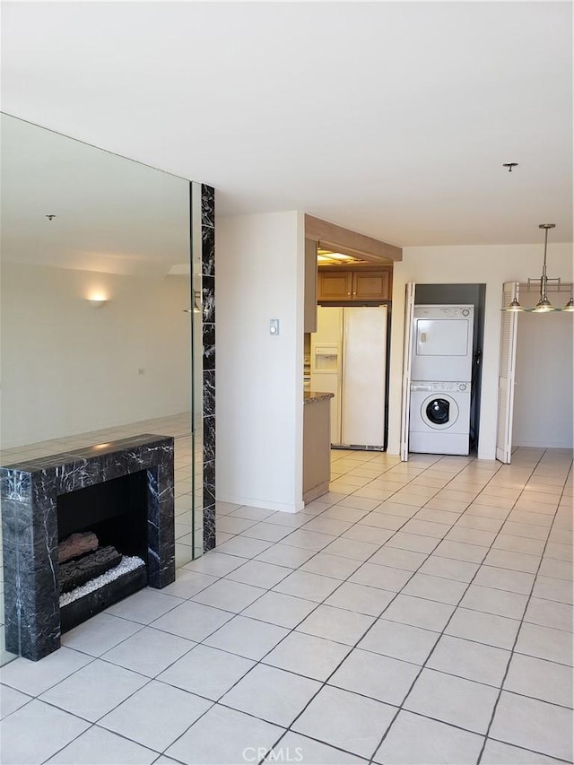 unfurnished living room with stacked washer / dryer, a high end fireplace, and light tile patterned floors