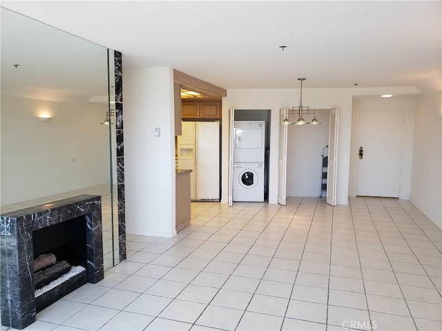 kitchen featuring stacked washer and dryer, white fridge with ice dispenser, decorative light fixtures, light tile patterned flooring, and a chandelier