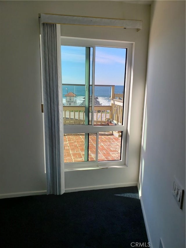 empty room featuring carpet flooring, a water view, and a view of the beach