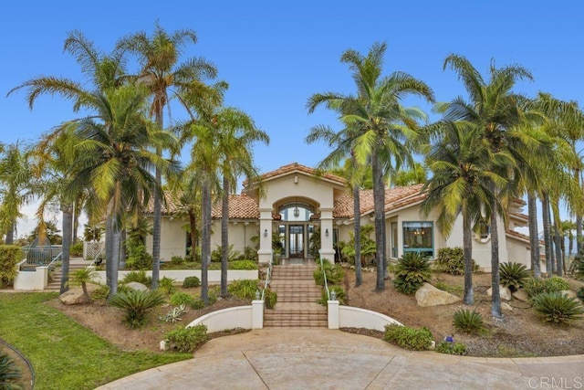 mediterranean / spanish house with french doors, stucco siding, a tile roof, and stairs