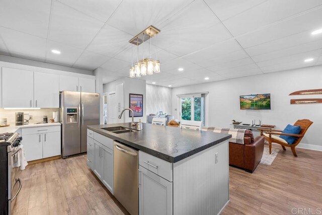 kitchen featuring light wood finished floors, open floor plan, a sink, and appliances with stainless steel finishes