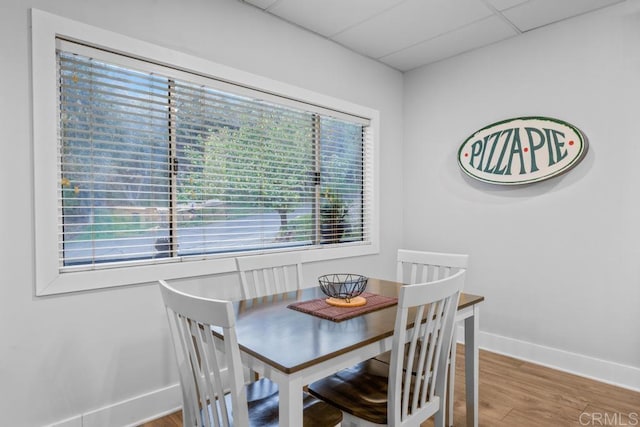 dining area with a paneled ceiling, wood finished floors, and baseboards