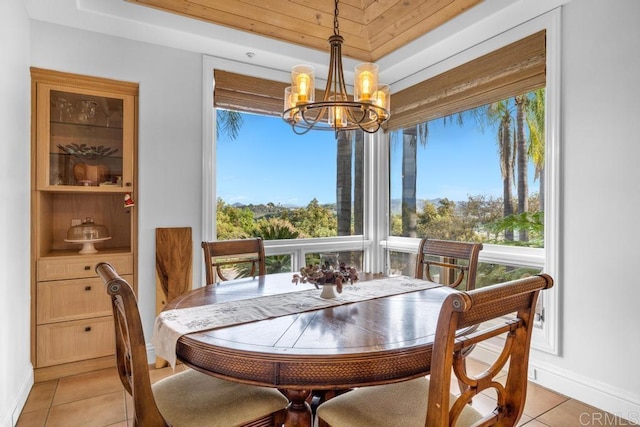 dining room with a tray ceiling, light tile patterned floors, a notable chandelier, and baseboards