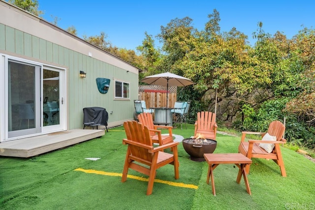 exterior space featuring a wooden deck, fence, and an outdoor fire pit