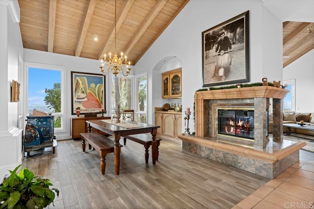 dining space with high vaulted ceiling, a fireplace, beamed ceiling, wooden ceiling, and hardwood / wood-style flooring