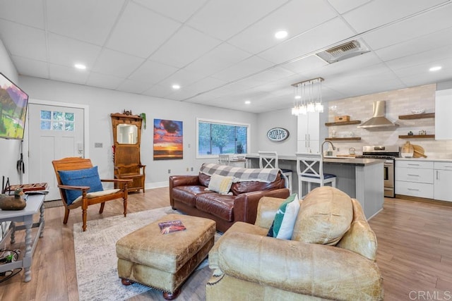 living room with a paneled ceiling, light hardwood / wood-style floors, and plenty of natural light