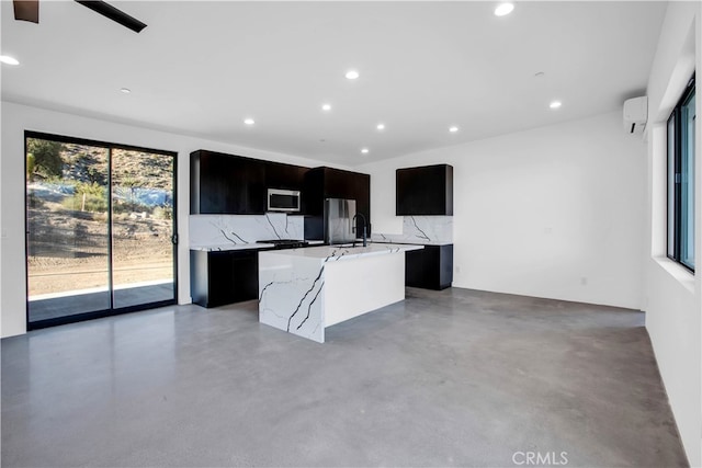 kitchen featuring a healthy amount of sunlight, a kitchen island with sink, stainless steel appliances, and backsplash