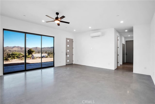 spare room featuring concrete floors, a wall mounted AC, a mountain view, and ceiling fan