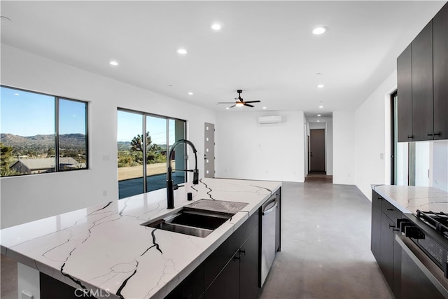 kitchen with sink, light stone counters, a wall mounted AC, appliances with stainless steel finishes, and a center island