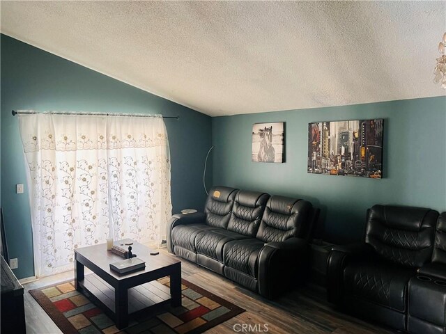 living room with a textured ceiling, vaulted ceiling, and hardwood / wood-style flooring