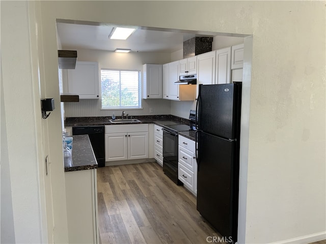 kitchen with black appliances, sink, white cabinetry, dark stone counters, and light hardwood / wood-style flooring