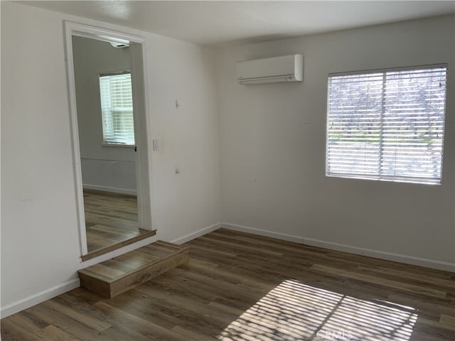 unfurnished room with dark wood-type flooring, an AC wall unit, and a wealth of natural light