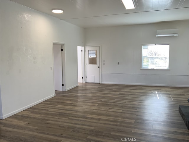 spare room featuring a wall mounted air conditioner and dark wood-type flooring