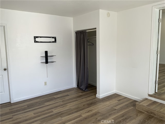 unfurnished bedroom with a closet and dark hardwood / wood-style flooring