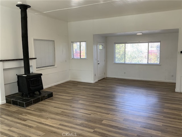 unfurnished living room featuring dark wood-type flooring and a wood stove