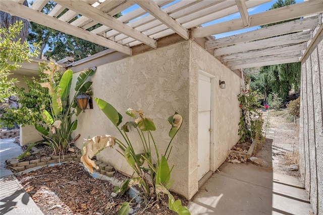 view of home's exterior with a pergola and stucco siding