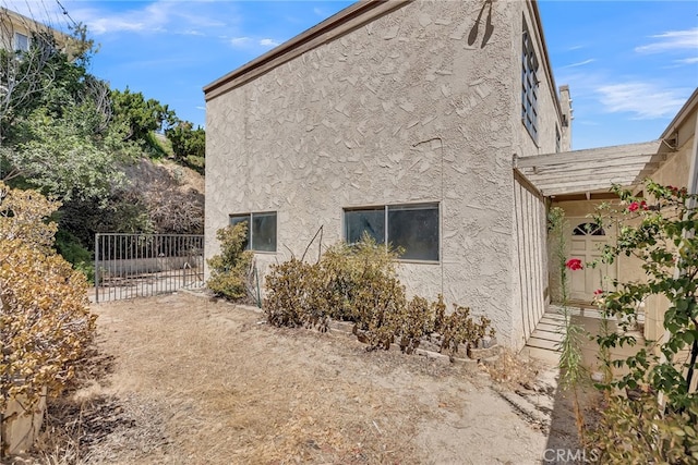 view of side of property featuring stucco siding and fence