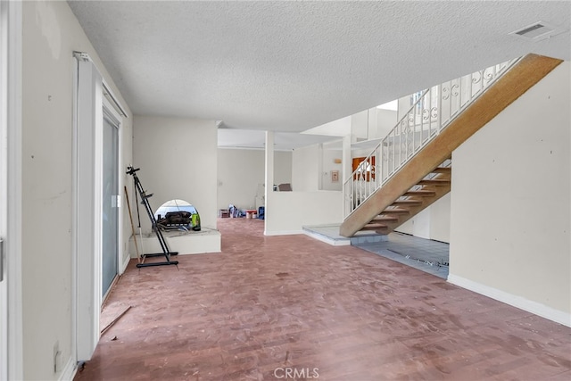 basement with wood finished floors, stairs, baseboards, visible vents, and a textured ceiling