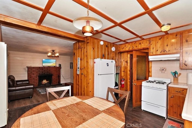 kitchen featuring wood walls, dark hardwood / wood-style floors, white appliances, and a brick fireplace