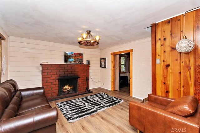 living room featuring hardwood / wood-style floors, a brick fireplace, and a chandelier