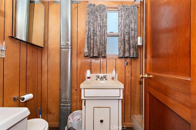 bathroom with vanity, toilet, and wooden walls