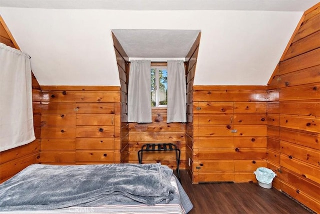 bedroom featuring dark wood-type flooring, wooden walls, and vaulted ceiling