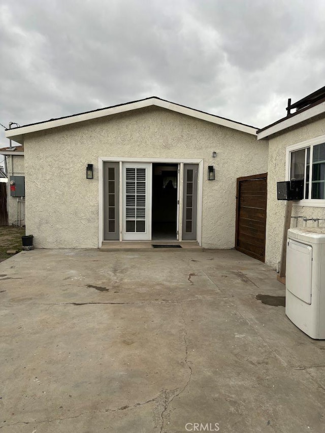 rear view of house with washer / clothes dryer, a patio area, and stucco siding