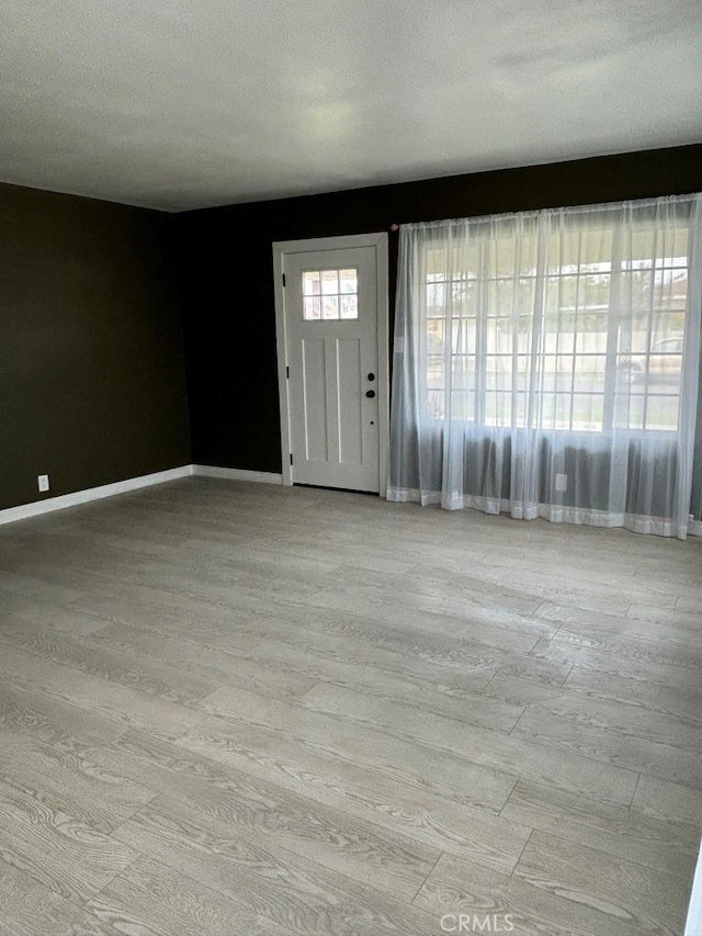 entryway with a textured ceiling, wood finished floors, and baseboards