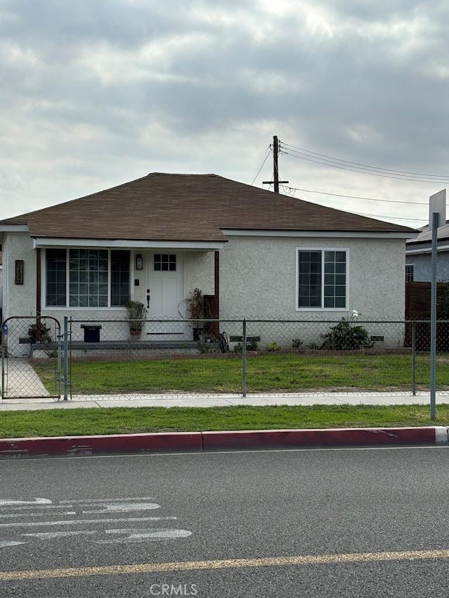 view of front of property with a shingled roof, a fenced front yard, a gate, and stucco siding