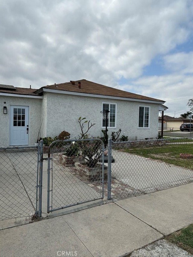 view of front of home with a gate, fence, and stucco siding