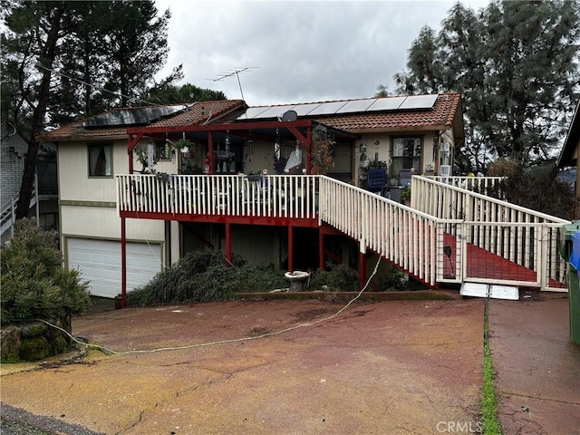 rear view of house with a garage and solar panels