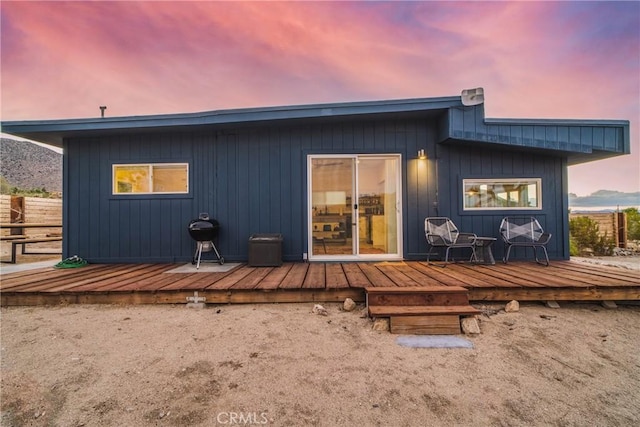 back house at dusk with a wooden deck