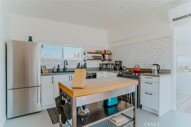 kitchen with backsplash, stainless steel appliances, a wall unit AC, sink, and white cabinetry