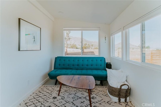 living area with a mountain view, plenty of natural light, carpet floors, and vaulted ceiling