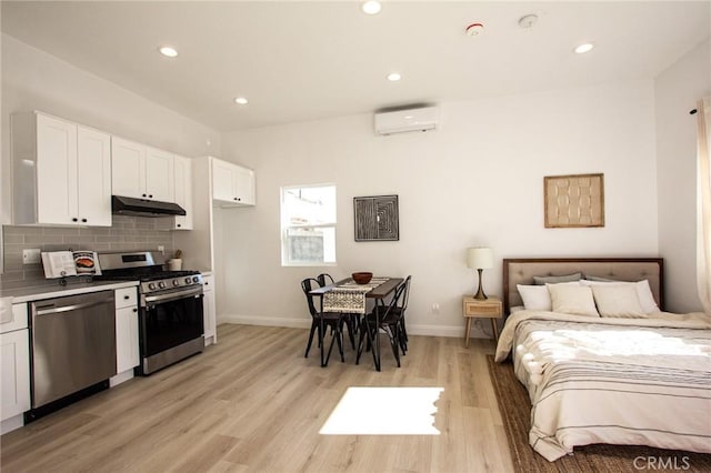 bedroom featuring light hardwood / wood-style flooring and a wall mounted AC