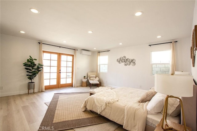 bedroom featuring french doors, light hardwood / wood-style flooring, and a wall mounted AC