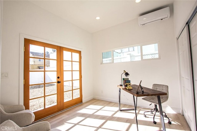 office featuring a wall mounted air conditioner, light wood-type flooring, and french doors