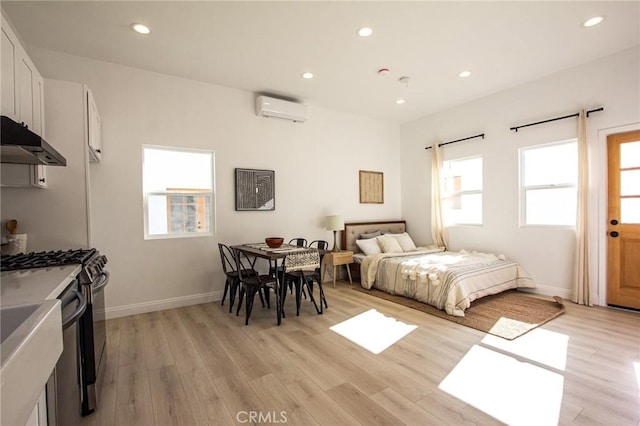 bedroom featuring a wall mounted AC and light wood-type flooring