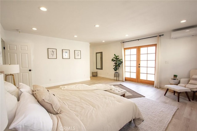 bedroom featuring a wall mounted AC, french doors, and light hardwood / wood-style flooring