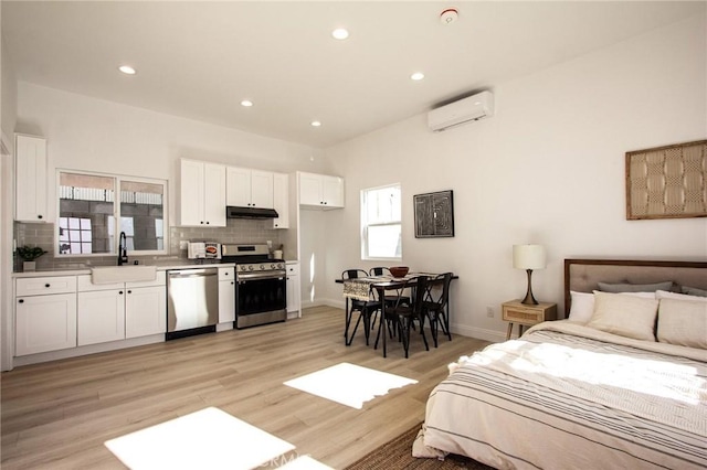 bedroom featuring light hardwood / wood-style floors, sink, and a wall mounted AC