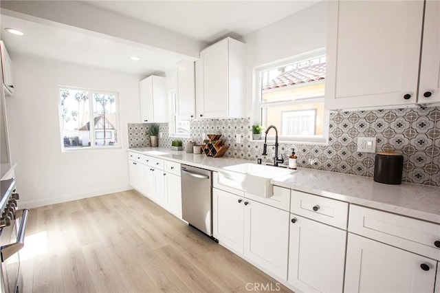 kitchen with sink, light hardwood / wood-style flooring, stainless steel dishwasher, white cabinets, and range